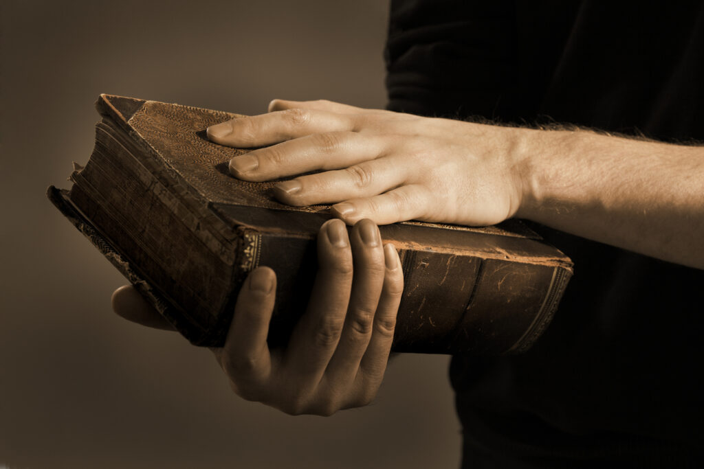 Hands holding very old book.